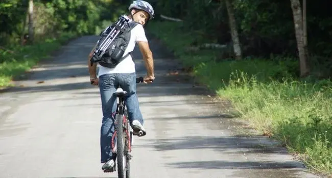 Keshi cycling through the jungle with his photography equipment