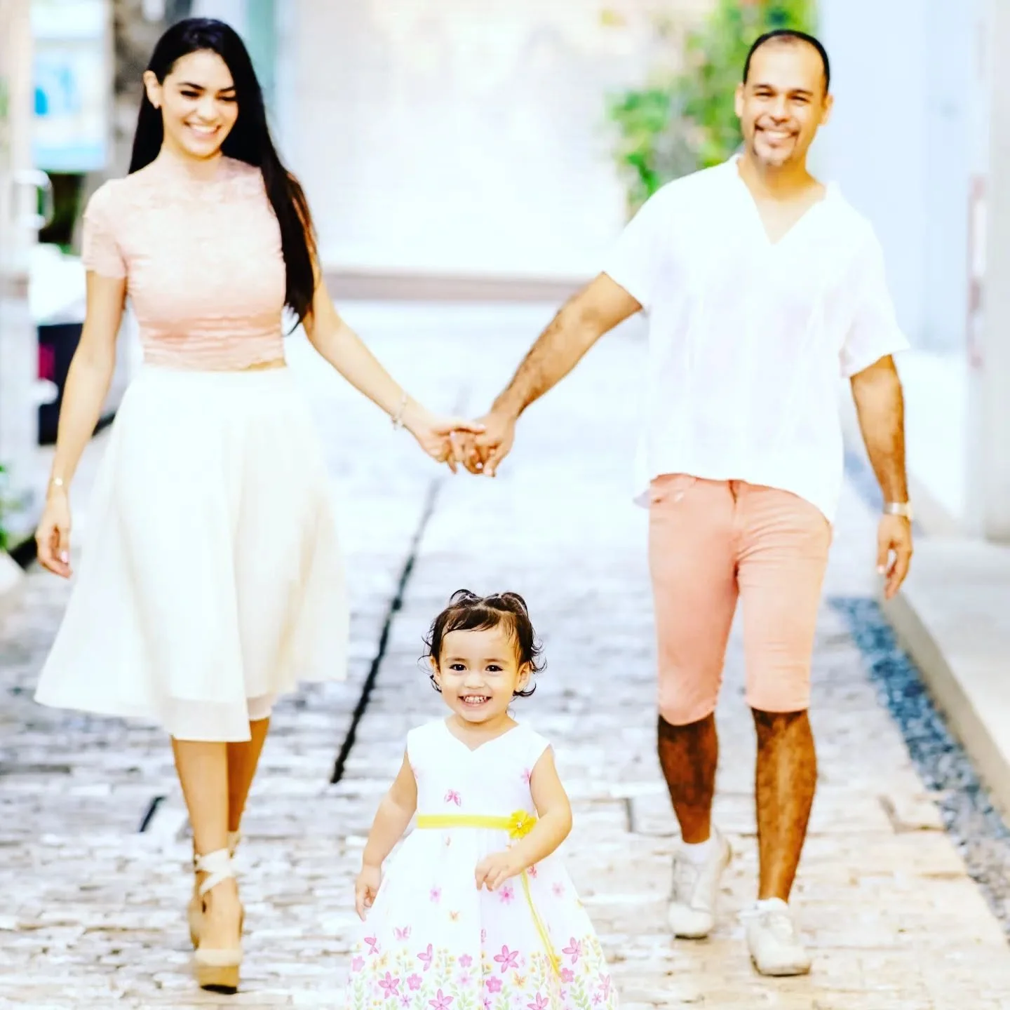 Lilian on the left and Keshi on the right, walking hand in hand behind their little daughter Juliette in the center.